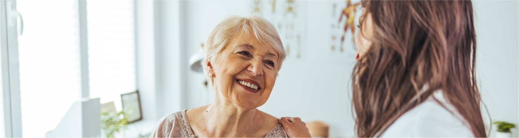 An older woman smiles while speaking with a healthcare provider in a clinic