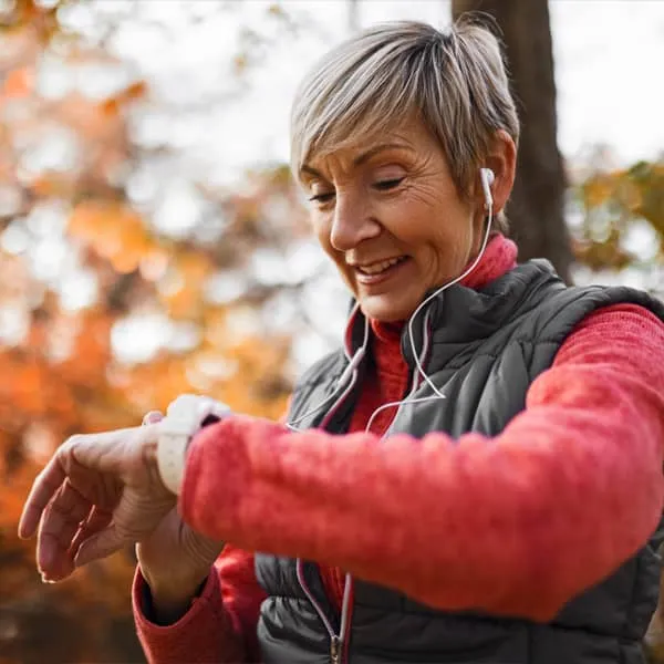 Smiling woman checking smartwatch while exercising outdoors