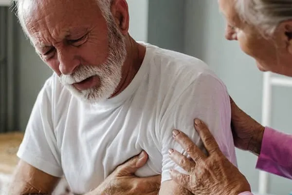 A man experiencing chest pain and shortness of breath, with his wife concerned about him.